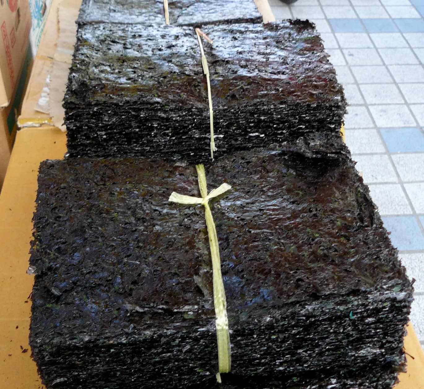 끈으로 묶어 쌓아 둔 검은 마른 김 묶음 두 덩이가 상자 위에 놓여 있다